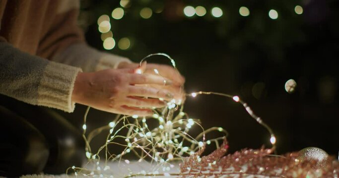 A woman untangles garlands, preparing for the meeting of Christmas and New Year