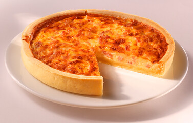 Quiche mit Schinken auf weisser Porzellanplatte