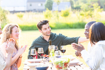 Experience the heartwarming camaraderie of a diverse group of friends as they come together for a delightful garden dinner party. Laughter and lively conversations fill the air as they enjoy food and