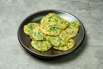 buchujeon, korean Chive Pancake, To prepare this dish, chive, julienned carrot, and green pepper are mixed with flour and pan-fried in a flat, round, pancake-like shape. 