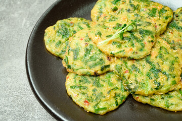 buchujeon, korean Chive Pancake, To prepare this dish, chive, julienned carrot, and green pepper are mixed with flour and pan-fried in a flat, round, pancake-like shape. 