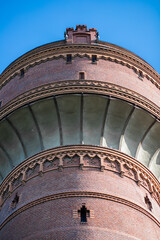 Fototapeta na wymiar Water tower to provide the population with water. Round tower against the blue sky. Red brick tower.