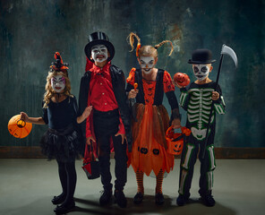 Group of children, little boys and girls in stylish costumes for halloween and creepy makeup over...