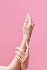 Vertical image of beautiful, tender young woman hands applying cream, scrub on her hands on pastel...