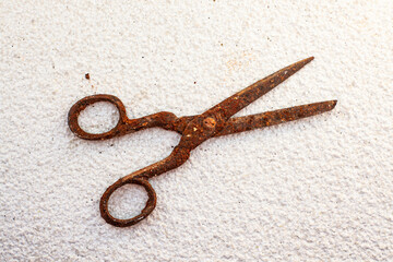 Old vintage scissors covered in rust on white stone background - isolated