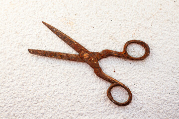 Old vintage scissors covered in rust on white stone background - isolated
