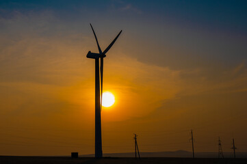 Obraz premium Windmill at sunset. Alternative energy source.