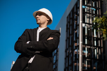 Fototapeta premium male foreman at a construction site looks at the quality of work, Architectural design holds a laptop at a construction site, checks plans. Successful engineer or architect, cheerful businessman.