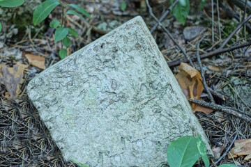 one old dirty large piece of white brick lies on the ground in the street