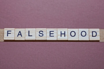 gray word falsehood made of wooden square letters on brown background