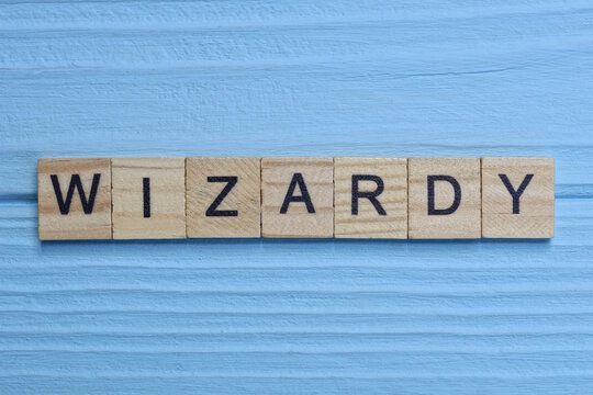 word wizardy made from wooden gray letters lies on a blue background
