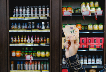 Argentinian Currency Devaluation. Man Holding Argentine Pesos Bills In The Supermarket. Shelves...