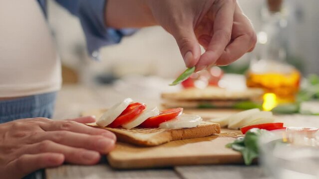 Caprese salad, young woman leisurely preparing caprese bruschetta in the kitchen. Follow up shot of a housewife cooking dish caprese follows the modern principles of morning food, cherry tomatoes