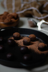 Chocolate truffles covered with cocoa powder. Gray background. Delicious dessert concept. Dark composition.