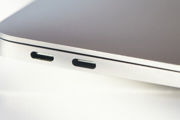 Two USB type-c ports on back side of the closed laptop. Notebook communication ports. High speed communication posts. New industrial standard of the computers connection peripheral. Close up view.