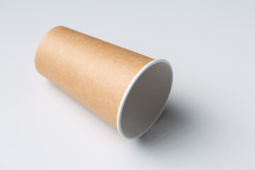 Disposable cardboard biodegradable glass on a white table, gray background.