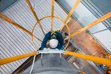 Top view male worker climbs down the ladder inspection stainless tank work at height safety