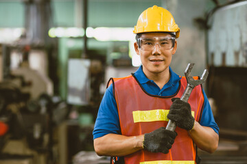Portrait Asian technician engineer male hand holding giant wrench happy smile. heavy industry...