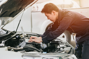 professional mechanic male work tune engine ignition timing in ecu with laptop computer in auto...