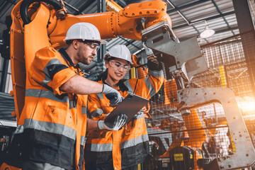 Engineer team service robot welding working in automation factory. People worker in safety suit...