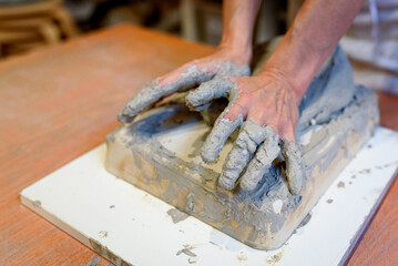 Close up of woman potter hands works with clay and ceramic, craftsman hands. knead and moistens the clay before work in ceramic and pottery workshop