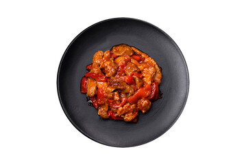 .Delicious juicy meat with hot peppers and sauce on a black ceramic plate
