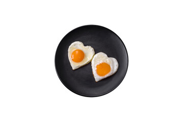 Two heart-shaped fried eggs on a black ceramic plate on a dark concrete background