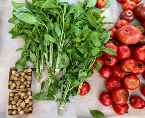 Flat lay of fresh red tomatoes with small bunches of basil and cape gooseberries or goldenberries for natural healthy food.