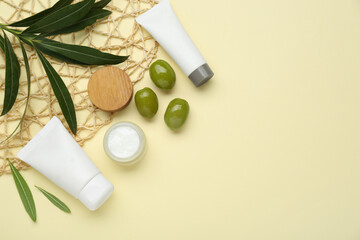 Cosmetic products with olive essential oil on beige background, flat lay. Space for text