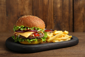 Delicious burger with beef patty and french fries on wooden table
