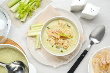 Delicious celery soup served on white wooden table, flat lay