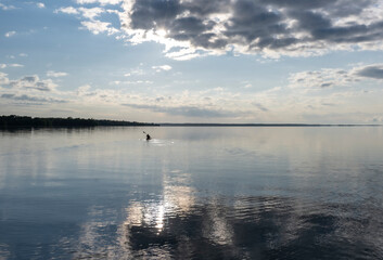 A woman kayaker paddling on a peaceful lake in Canada with sky reflected in the water