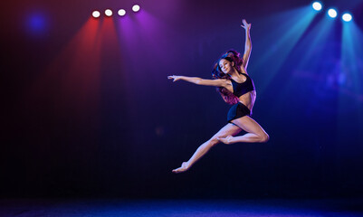 young performer of modern choreography dancing in the spotlights on a black background.