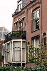 part of typical red building in Amsterdam, Netherlands, summer, green trees, cloudy