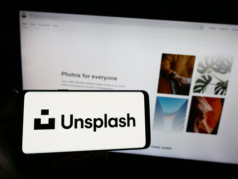Stuttgart, Germany - 08-18-2023: Person holding smartphone with logo of stock photography company Unsplash Inc. on screen in front of website. Focus on phone display.