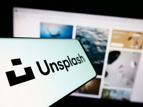Stuttgart, Germany - 08-18-2023: Cellphone with logo of stock photography company Unsplash Inc. on screen in front of business website. Focus on center-left of phone display.