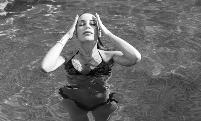 Fototapeta premium European blonde beautiful woman in pool. Travels and vacation concept, blue water and tan body