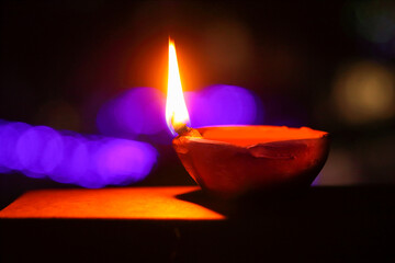 A glowing earthen ghee lamp in the dark. Diyas of diwali (deepawali) lined up in preparation of the...