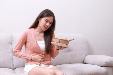 Asian woman having diarrhea after eating a box of food. Choosing a healthy diet. Chronic diarrhea...