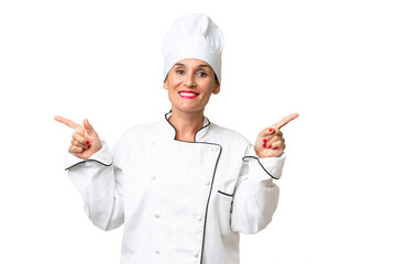 Middle-aged chef woman over isolated background pointing finger to the laterals and happy