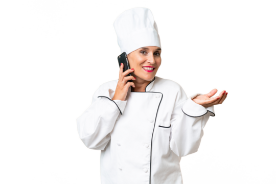 Middle-aged chef woman over isolated background keeping a conversation with the mobile phone with someone