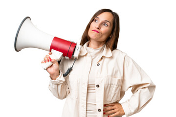 Naklejka premium Middle-aged caucasian woman over isolated background holding a megaphone and thinking