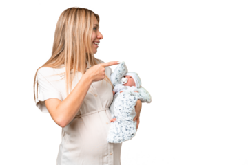 Young pretty pregnant woman with her newborn baby over isolated chroma key background pointing to the side to present a product