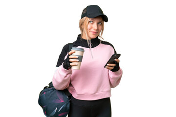 Pretty sport woman with sport bag over isolated chroma key background holding coffee to take away and a mobile while thinking something