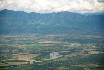 Naklejka premium Aerial view of a river with crop fields around it in a tropical climate in the department of Huila. Colombia.