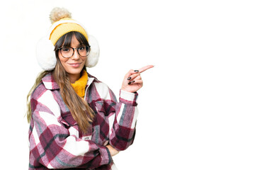Young caucasian woman wearing winter muffs over isolated chroma key background pointing finger to...