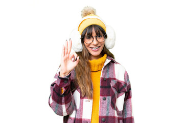 Young caucasian woman wearing winter muffs over isolated chroma key background showing ok sign with fingers