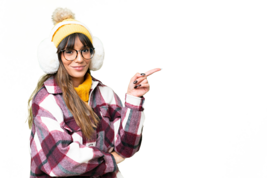 Young caucasian woman wearing winter muffs over isolated chroma key background pointing finger to the side