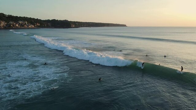 Coastline, sunrise or sunset tones and ocean with surfers and waves in Bali. Aerial view