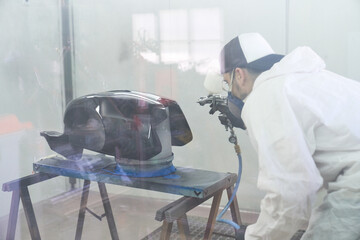 Focused male mechanic spraying paint on tank